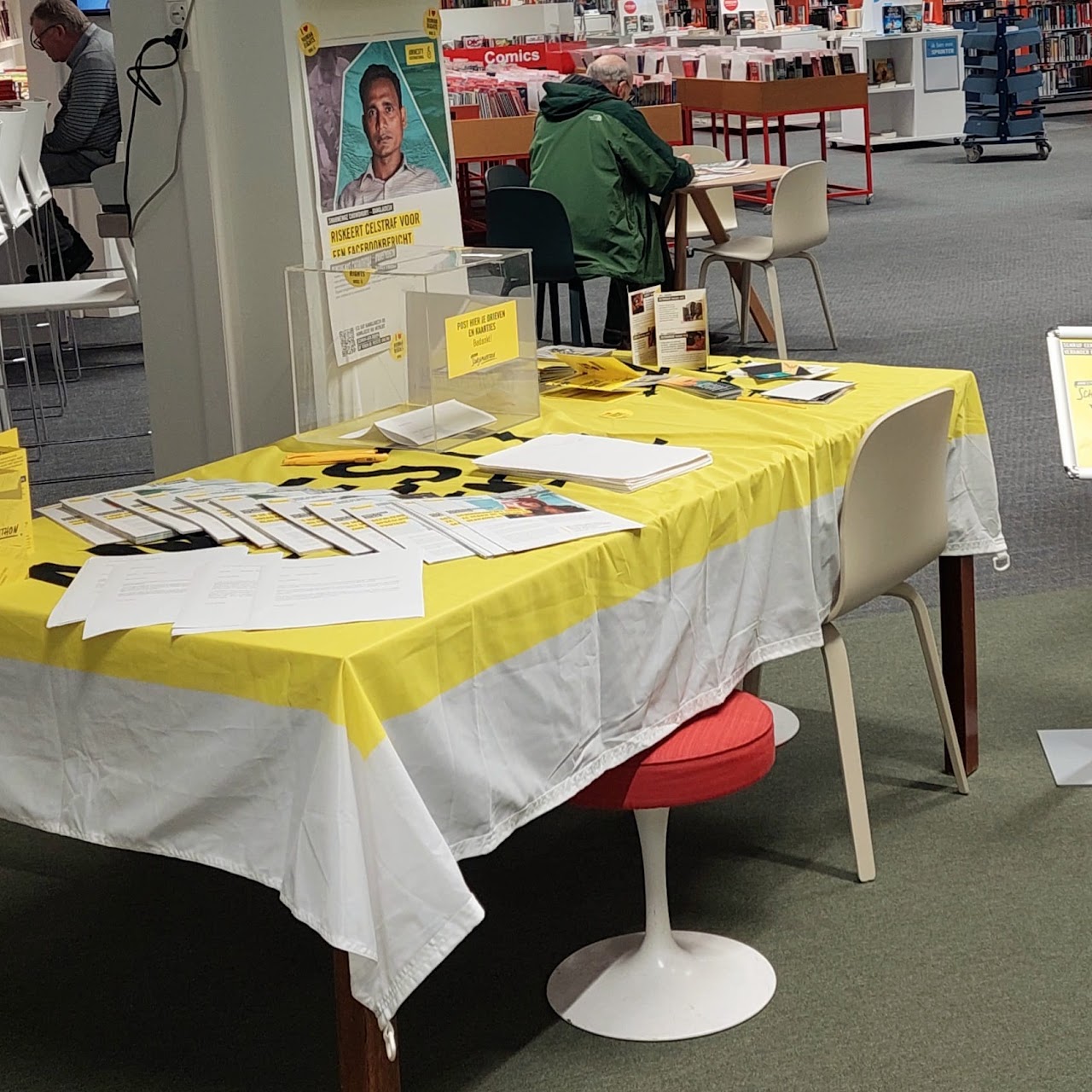 Een tafel op een evenement met petities en posters