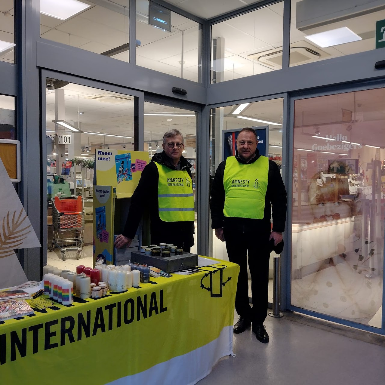 Een tafel aan de ingang van een supermarkt met kaarsen van Amnesty International te koop uitgesteld